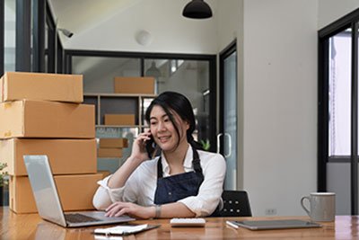 young business owner on the phone surrounded by boxes